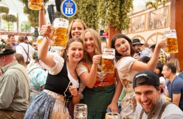 Munich, Germany - September 21, 2019: Oktoberfest in Munich, Germany. A group of young people in beer hall, celebrating Oktoberfest on Theresienwiese. People are dressed in traditional clothes and holding beer glass. The Oktoberfest is the largest fair in the world and is held annually in Munich.